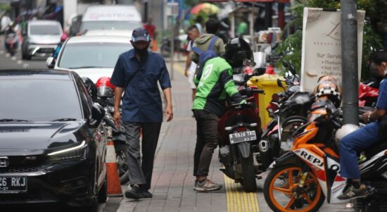 Pejalan kaki melintasi trotoar yang sempit akibat okupasi parkir liar di Jalan Blora, Menteng [MI/Usman Iskandar]