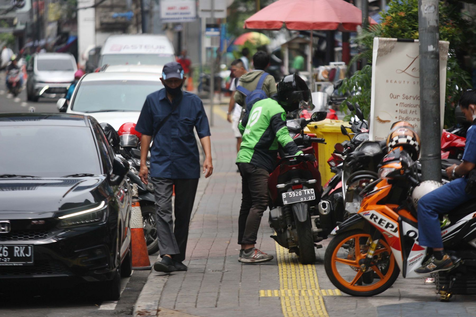 Pejalan kaki melintasi trotoar yang sempit akibat okupasi parkir liar di Jalan Blora, Menteng [MI/Usman Iskandar]